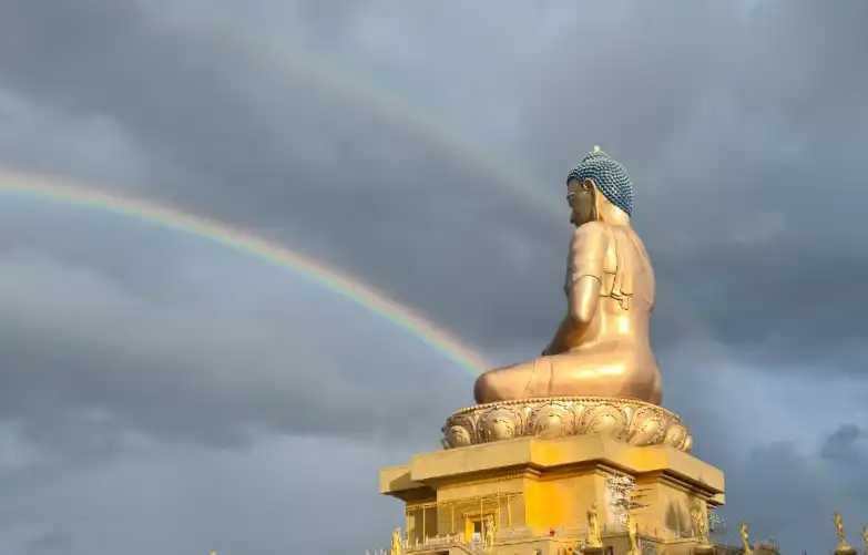 Colossal bronze Buddha Dordenma statue under a vibrant rainbow in Thimphu, Bhutan